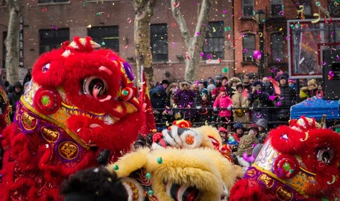 Leeuwendans en confetti in een drukke viering van Chinees Nieuwjaar in Chinatown, New York.